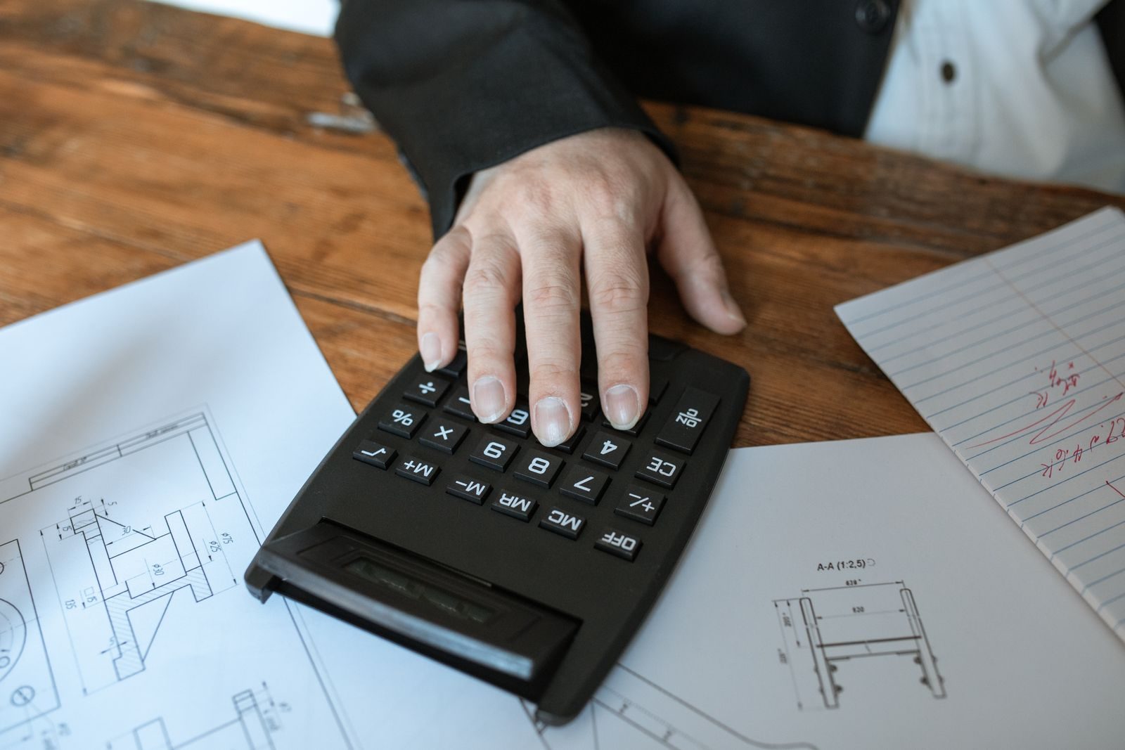 Calculator, pen and plans on a desk